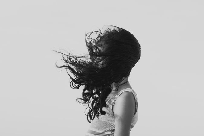Side view of woman's flying hair against light background in grayscale