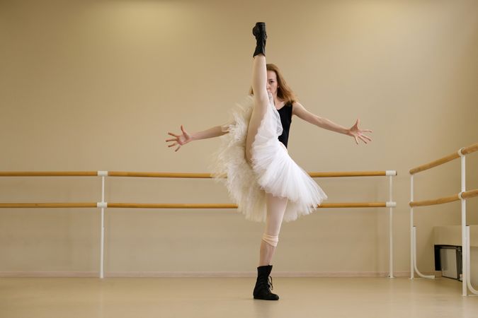Ballerina in shoes and tutu, balancing with arms wide