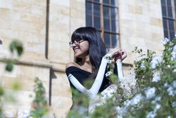 Portrait of beautiful woman smiling while looking away standing behind a hedge