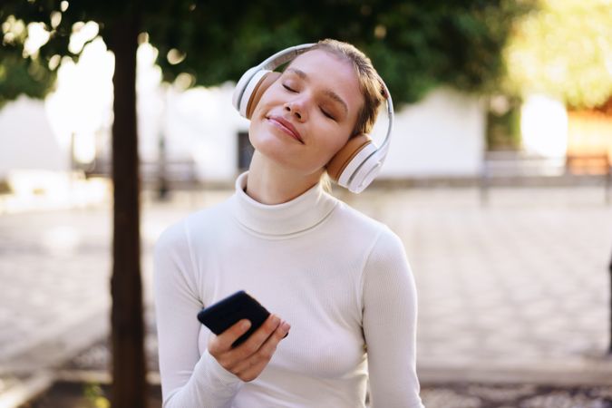 A Woman Enjoying Music Outdoors While Wearing Headphones in a Relaxing Environment