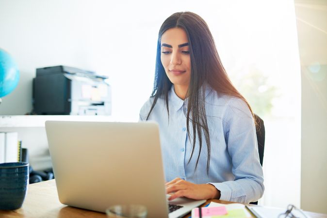 Woman concentrating on writing on laptop in her office