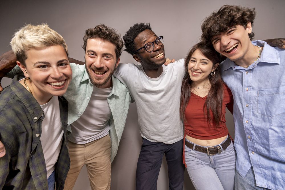 Happy multiracial group of friends smiling at camera in studio with casual clothes and joyful expressions