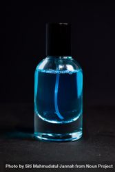 Light blue perfume bottle in dark studio with space for text 4AzmdE