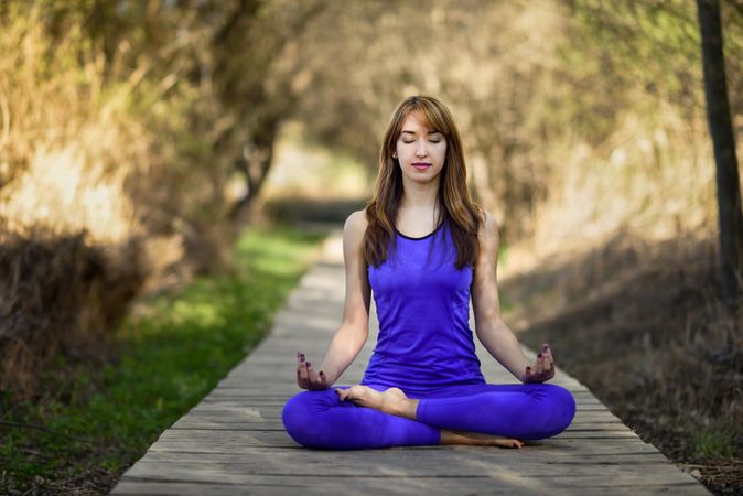Female wearing purple sport clothes in lotus pose