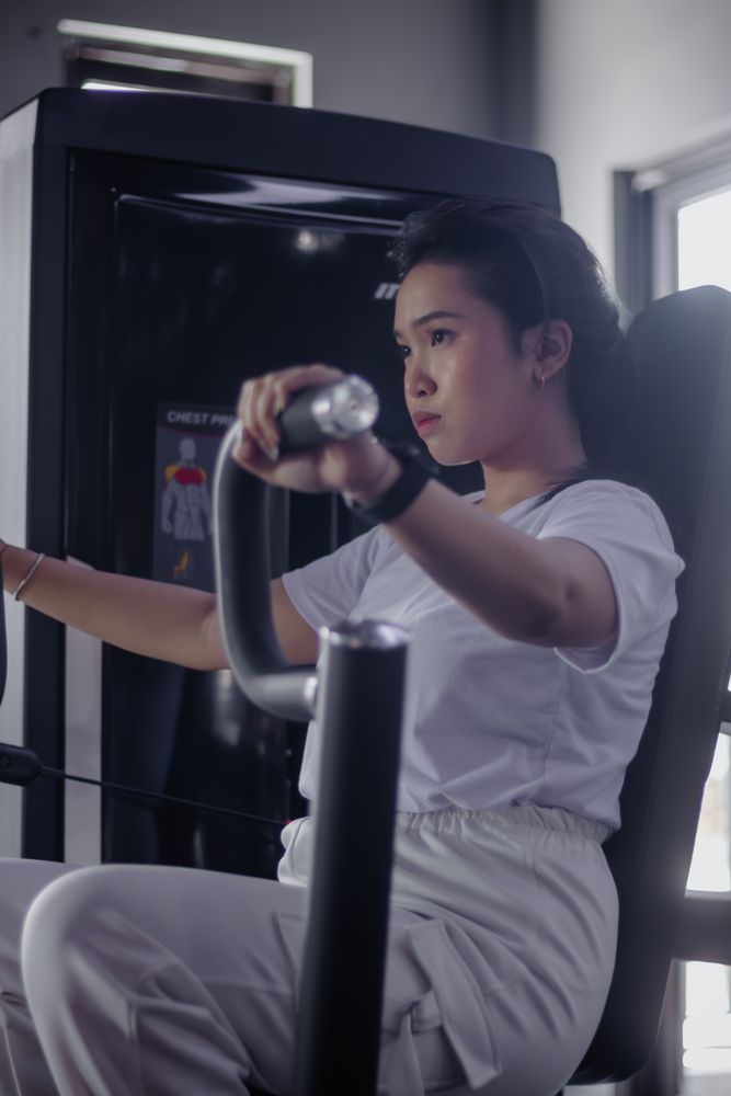 Dedicated young woman using chest press machine at modern fitnes
