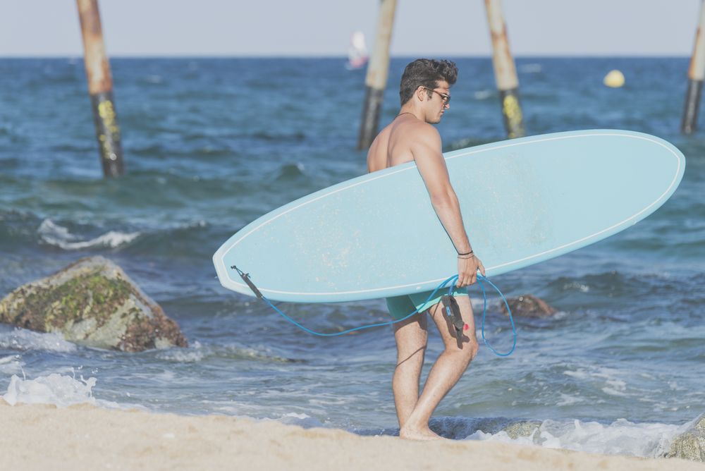 Male surfer holding surfboard approaching the shore