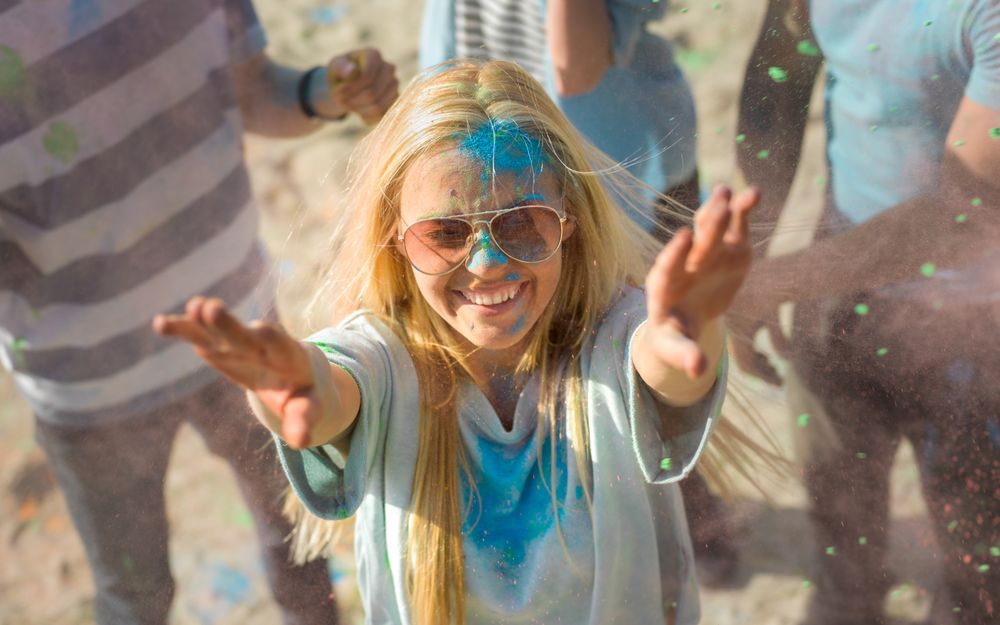 High Angle Shot of a Blonde Woman Throwing Colorful Powder in the Crowd Amidst Hindu Holi Festival Celebrations.