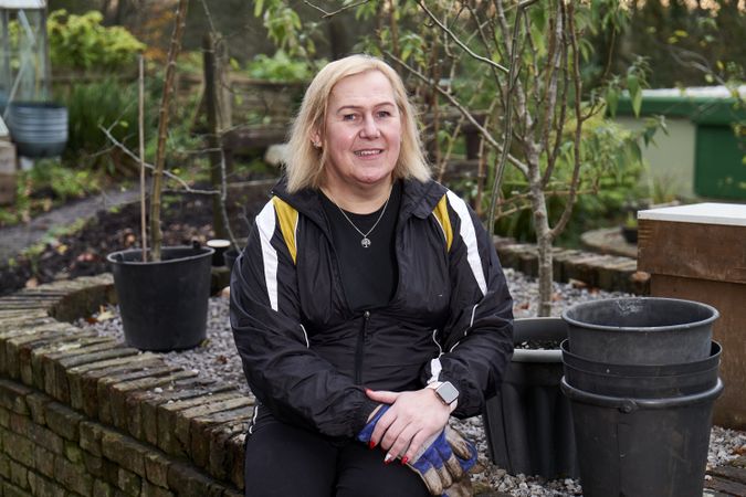 Woman sitting on brick wall in garden