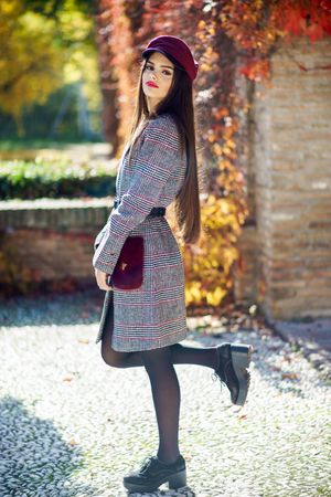 Serious female in warm winter clothes standing outside on sunny day