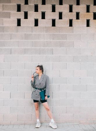 Stylish businesswoman with laptop leaning on wall