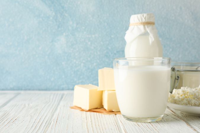 Different dairy products on wooden table against blue background, copy space