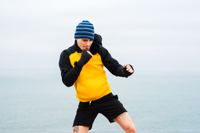 Kickboxer training on cliff near sea