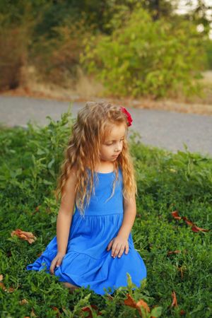 Female child playing in grass in blue dress