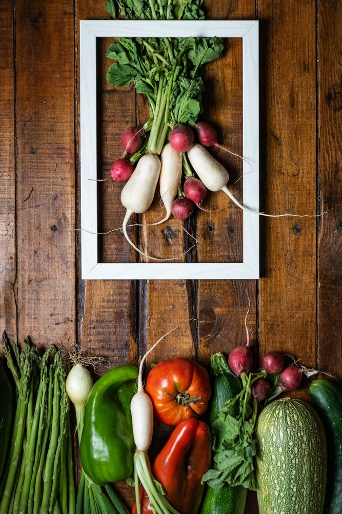 Composition with vegetables and white frame in wooden table