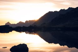Calm lake in sunset light surrounded by mountains