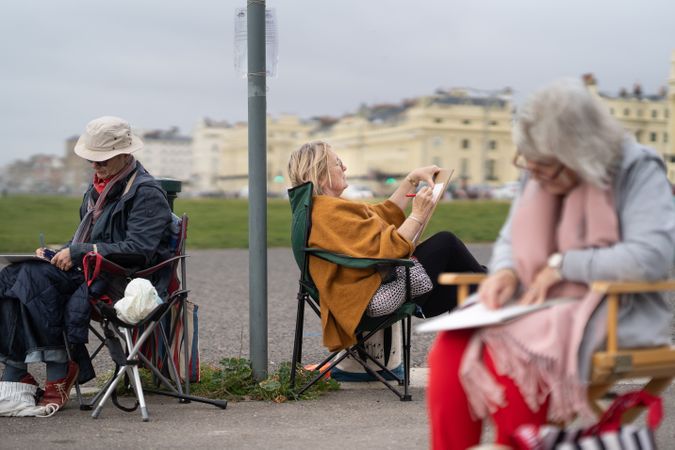 Group of people sitting outside in park at drawing class