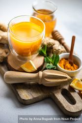 Ginger turmeric drink & ingredients on wooden cutting board 49mBBa