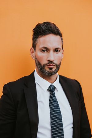 Adult stylish man in costume near orange wall