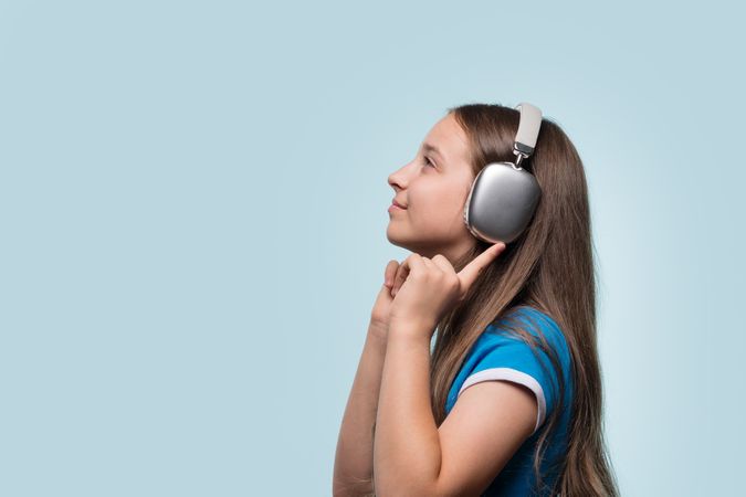 Young girl with headphones, listening to music and smiling.