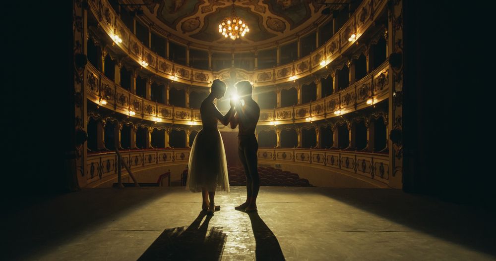Cinematic shot of Young Couple of Classical Ballet Dancers Performing on the Stage of Classic Theatre with Dramatic Lighting.