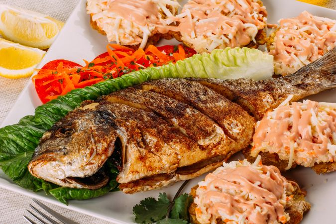 Top view of fried fish, salad and fried plantain
