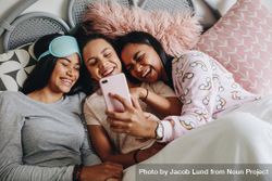 Young women lying on bed laughing while looking at a mobile phone 5pqQO4