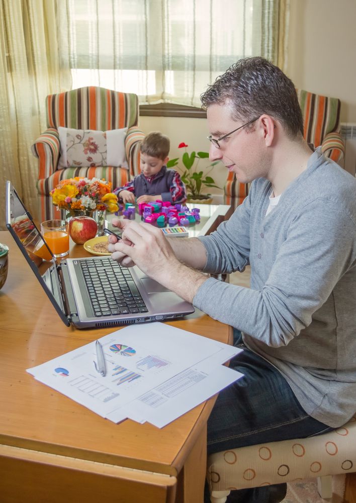 Father working in home office and son playing