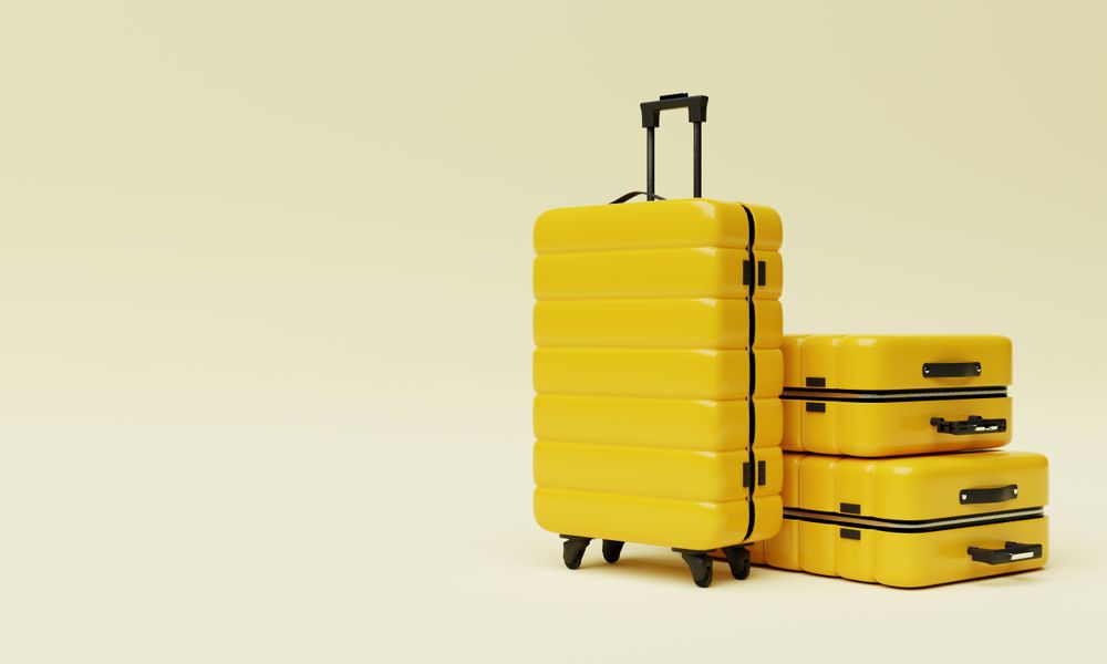 Three yellow hard shell roller suitcases on light yellow background