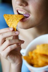 Close up of girl snacking on nacho chips