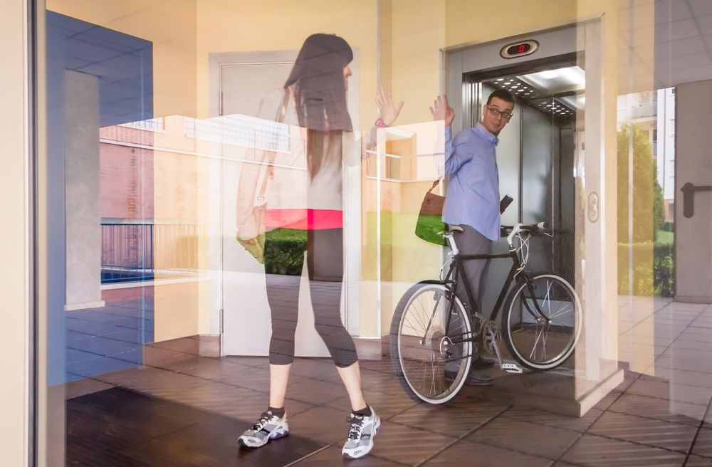 Businessman and sportive woman waving behind glass