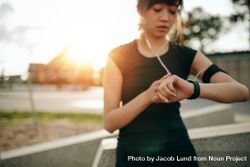 Close up shot of young woman jogger ready to run looking at smartwatch 4MAZ14