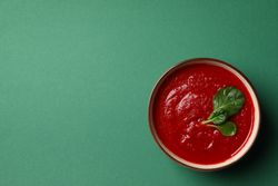 Looking down at bowl of tomato soup on green table with copy space