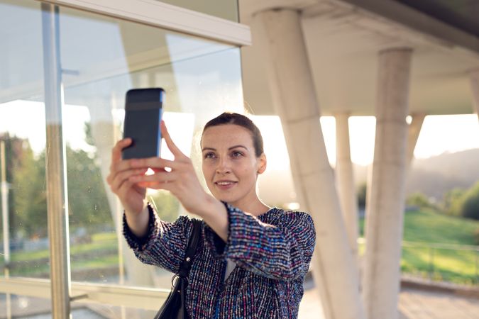 Smiling businesswoman taking selfie on street