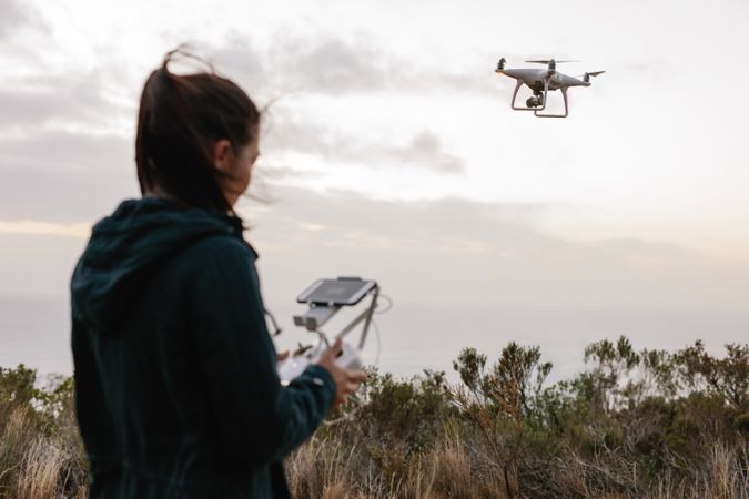 Woman operating a drone against a cloudy sky