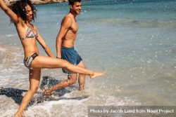 Cheerful woman splashing water with her leg enjoying on the beach 5o6kG0