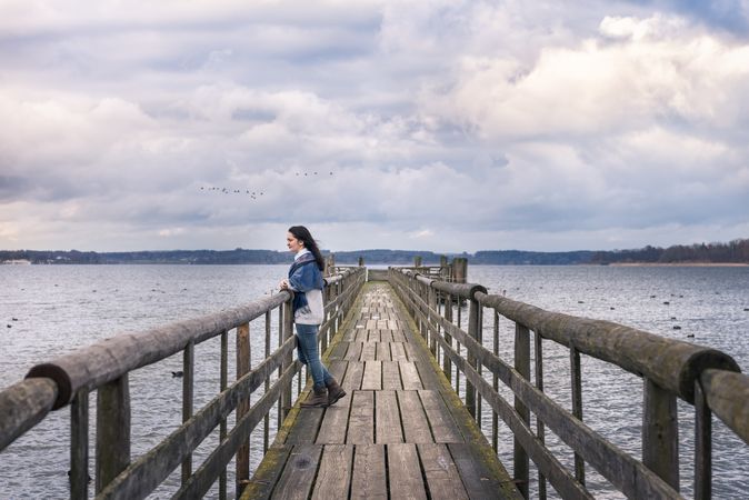 Woman standing on bridge looking out over a lake