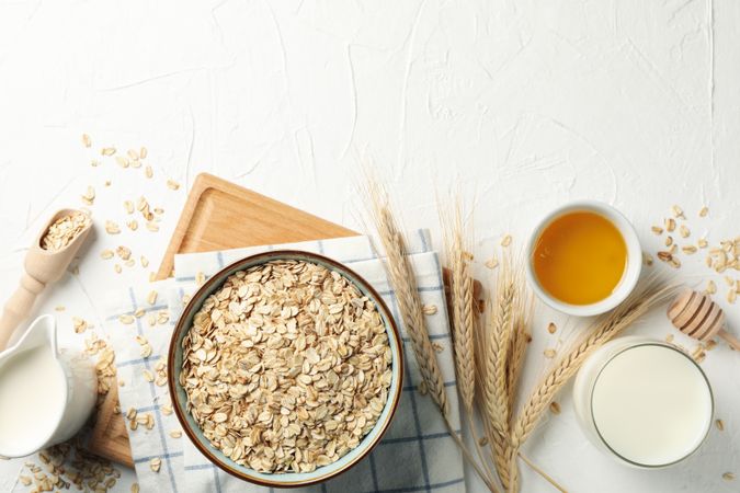 Composition with oatmeal flakes on plain background, top view. Cooking breakfast
