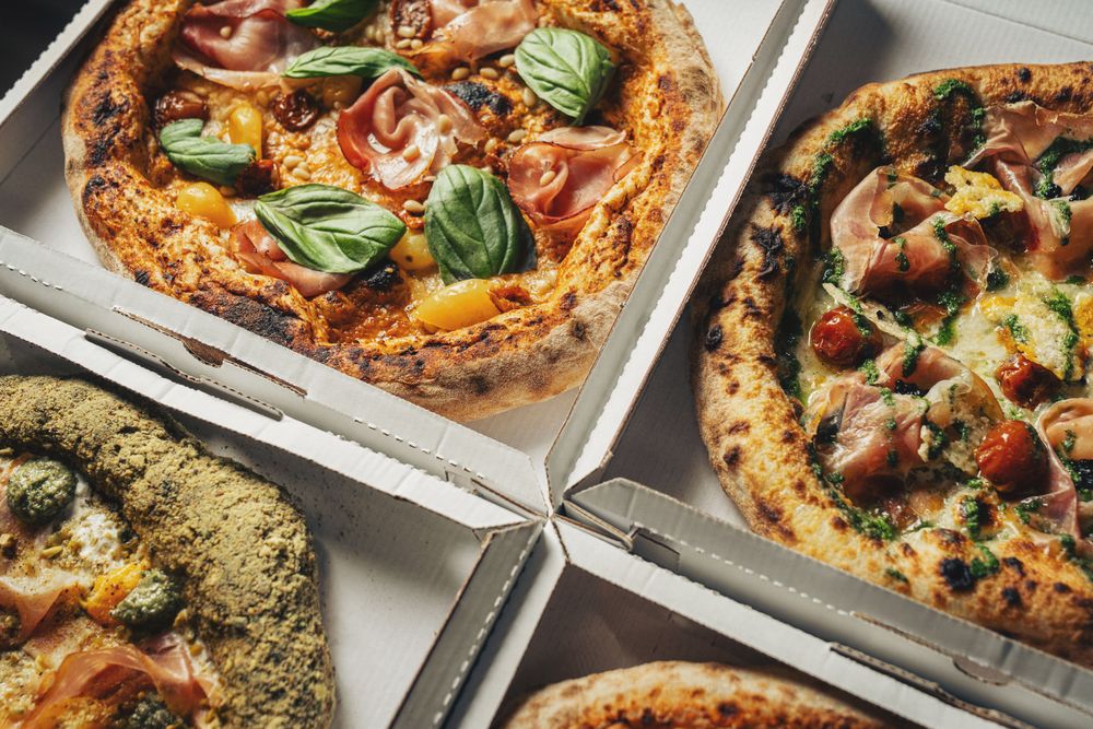 Gourmet artisan pizzas with fresh toppings in delivery boxes close-up