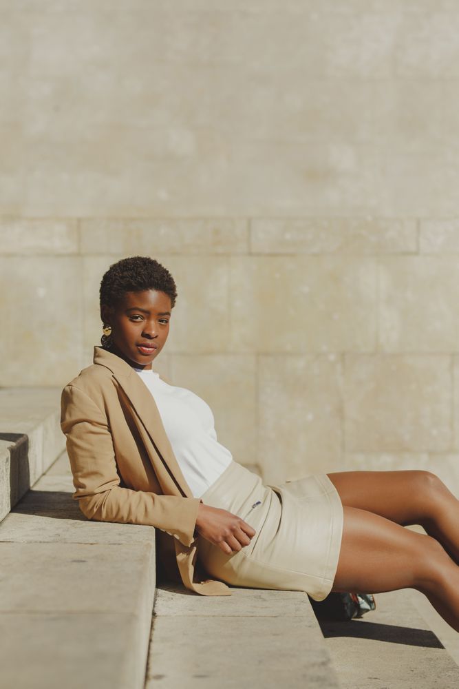 Stylish Black woman sitting on steps on street