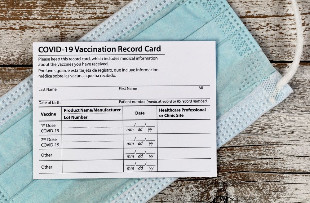 Covid 19 vaccination record card with facemask in close up view
