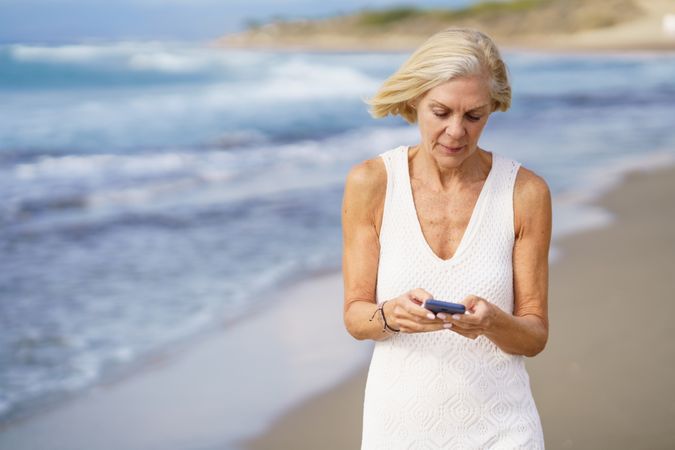 Mature female using her smart phone on the beach