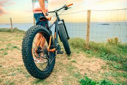 Male standing with bicycle looking down at beautiful beach