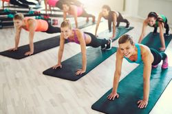 Group of smiling women doing planks in gym class