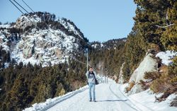 Man with smartphone between hills with trees in winter
