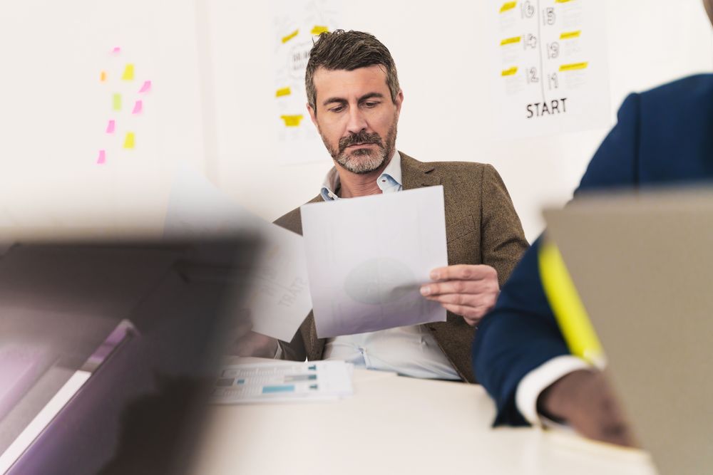 Mature manager analyzing project documents in office