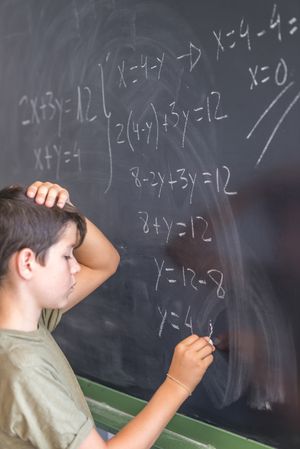 Teenager solving equation at chalk board