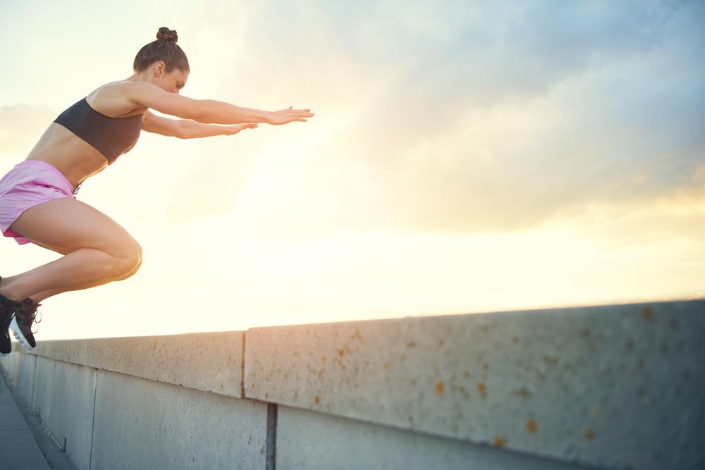 Woman practicing box jumps in pink shorts