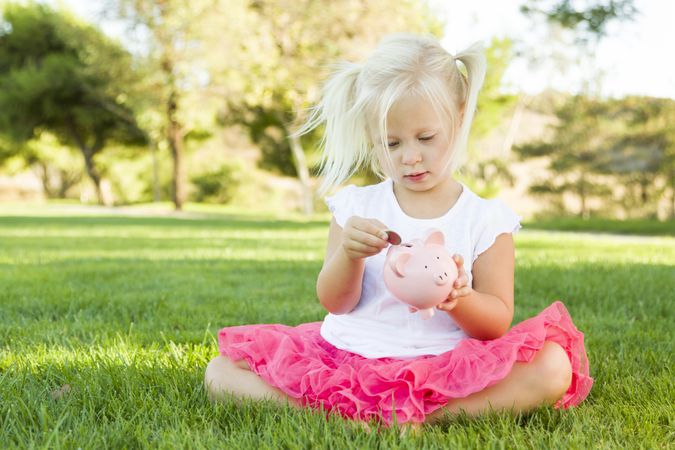 Little Girl Having Fun with Her Piggy Bank Outside