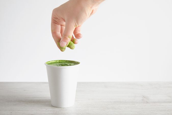 Hand sprinkling matcha powder on drink