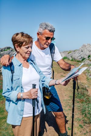 Vertical composition of older couple checking map during a trek